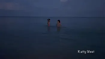 Two naked sluts play with each other in the sea on a public beach